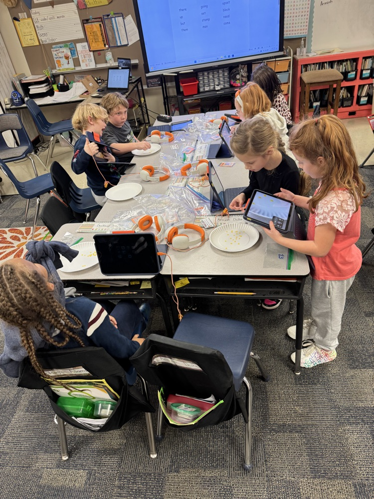 group of students around a table with laptops. 