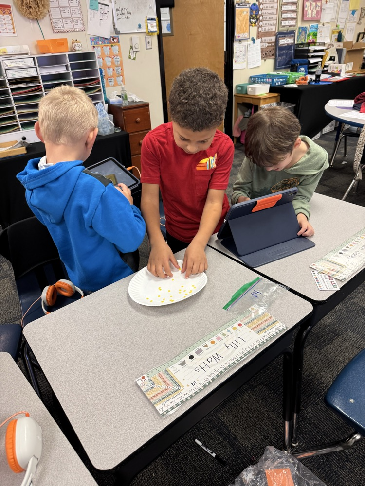three boys at desks with a plate 