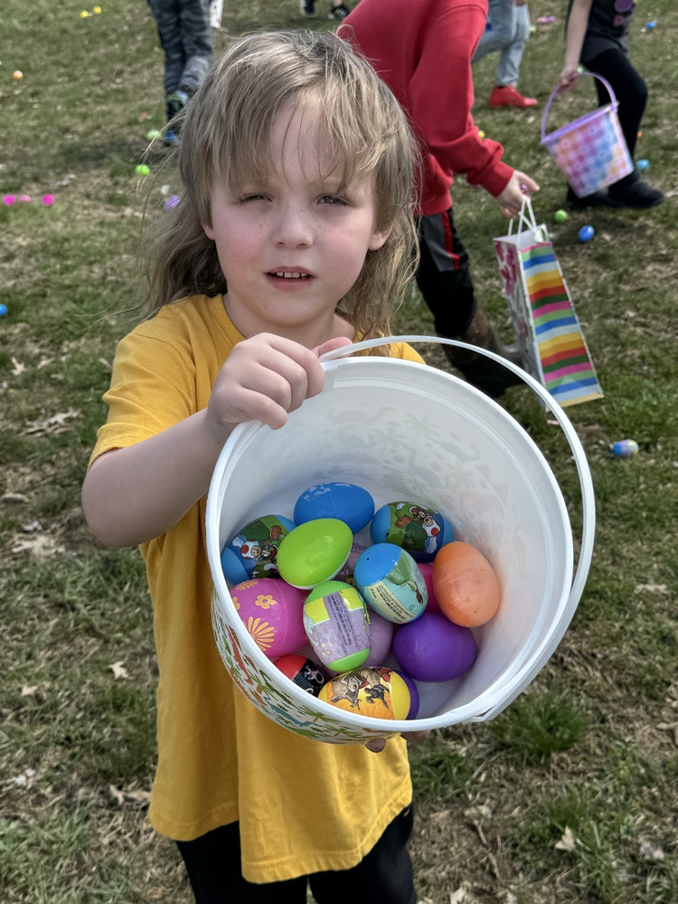 student in yellow shirt holding a bucket of eggs