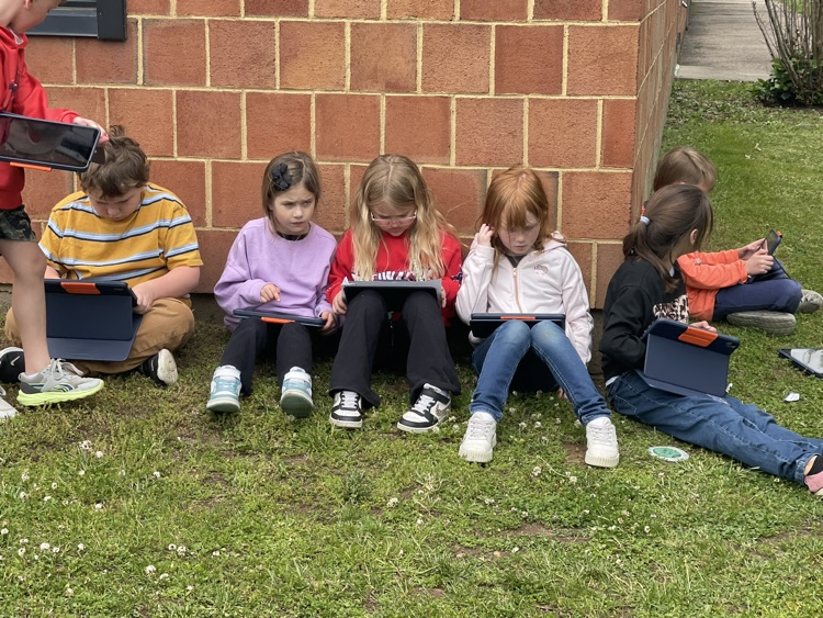 student sitting along the school building in a line 