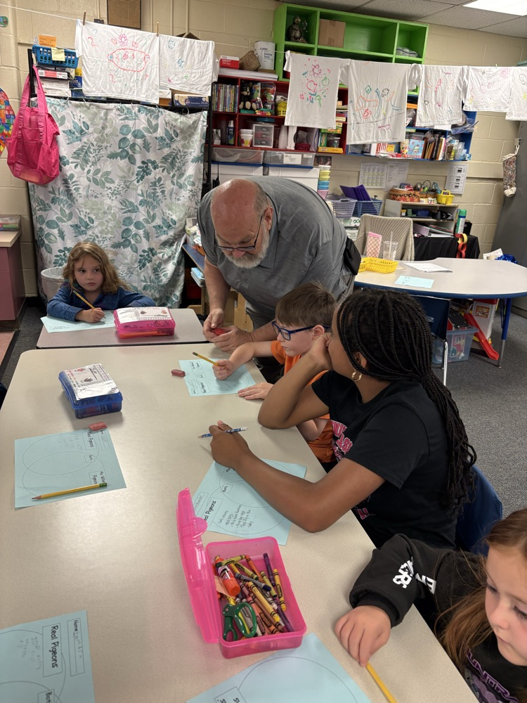 male teacher assisting a group of students at a table. 