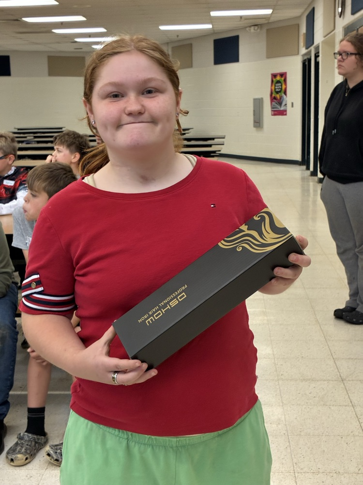 student in red shirt and green shorts holding a reward
