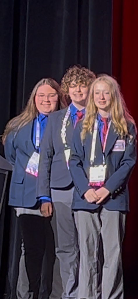 Alyssa Kelley, Amelia McPherson, and Lily Giovinazzo on stage at TSA Nationals. 