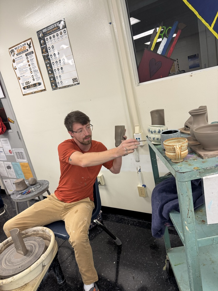 Jake Pierce explaining how glaze works on a piece of pottery  
