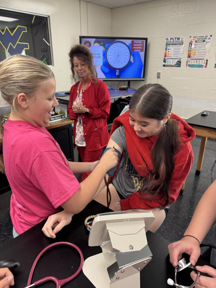 Gracie Bosely prepares to take Gigi Frinks blood pressure while Nurse Long looks on to ensure proper technique  