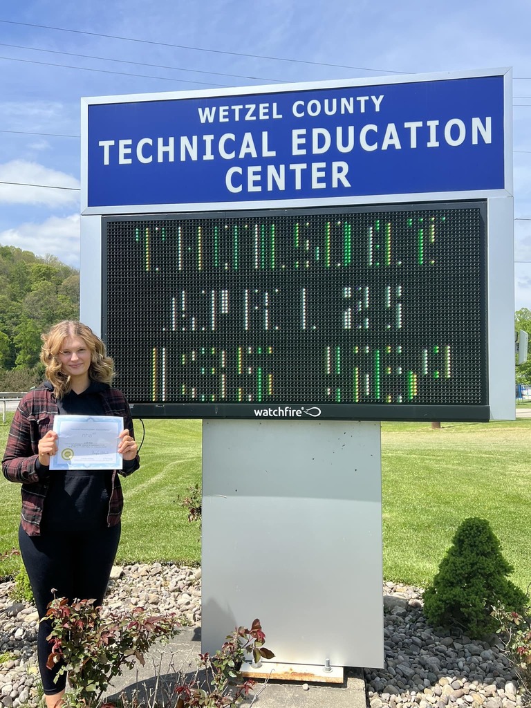 student with certificate in front of sign