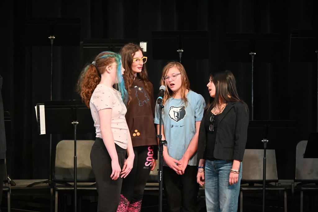 Four WF students surrounding the microphone for their piece of the concert