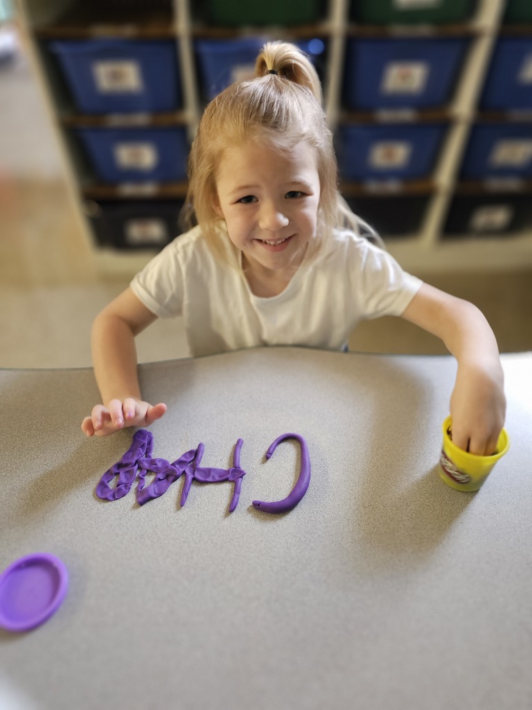 Happy student making letters with  playdoh
