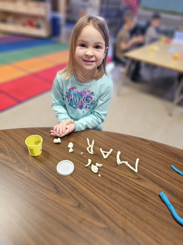 Happy student making letters with  playdoh