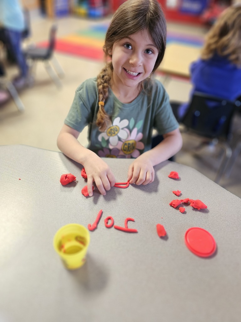 Happy student making letters with  playdoh
