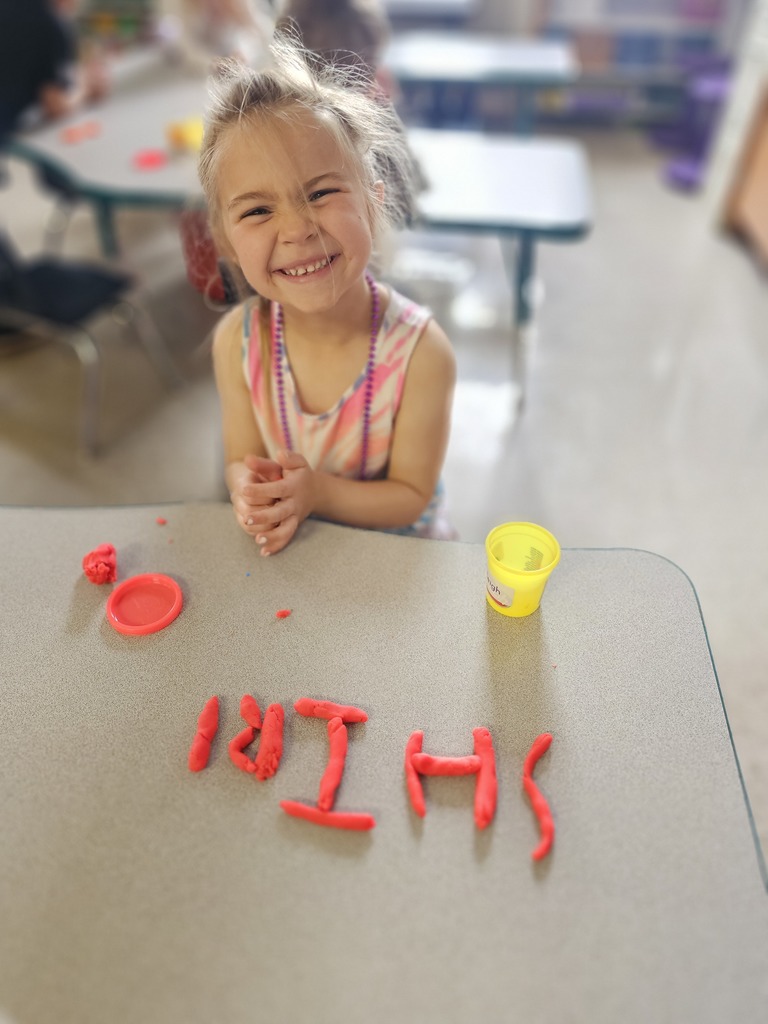 Happy student making letters with  playdoh