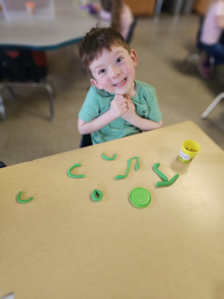 Happy student making letters with  playdoh