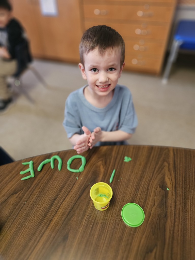 Happy student making letters with  playdoh