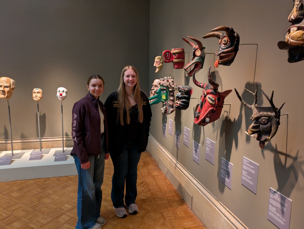 Two students smile next to a display of masks 