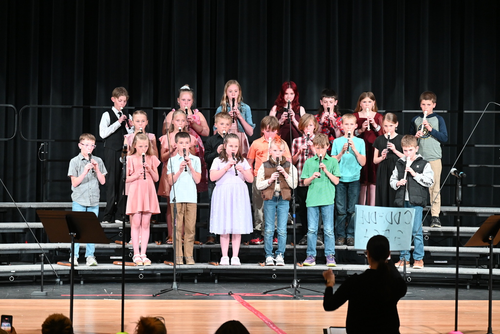 A group of students playing their recorders on stage. 