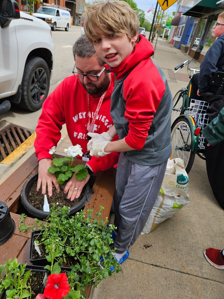 A quick look from a student while helping to fill the planter with red and white flowers