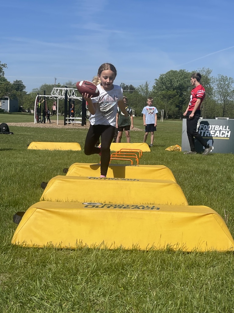 A student leading with the football while completing the obstacle course