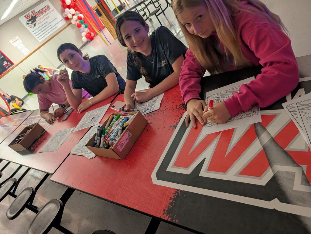 Students stopping to smile at the camera while coloring Glow Dance pages