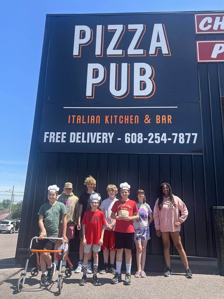 Student gathering for a picture in front of the Pizza Pub sign