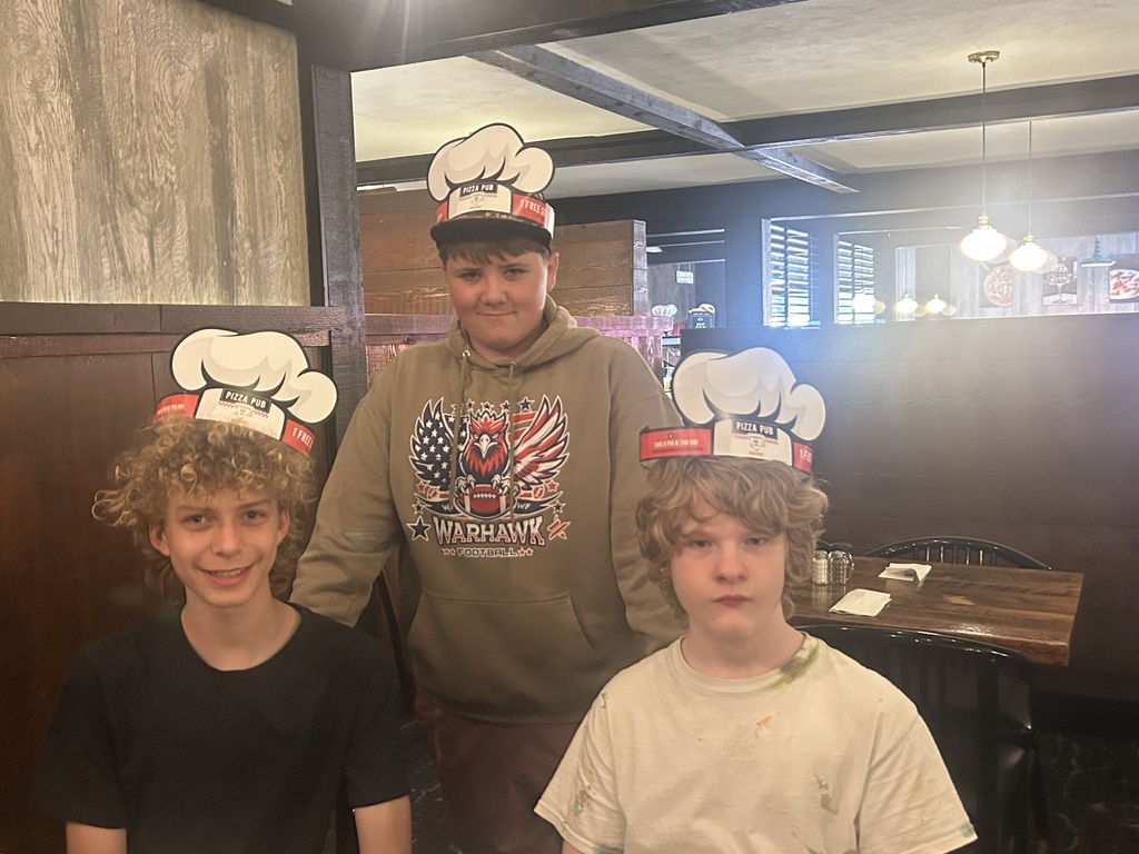 Three students posing with special Pizza Pub hats