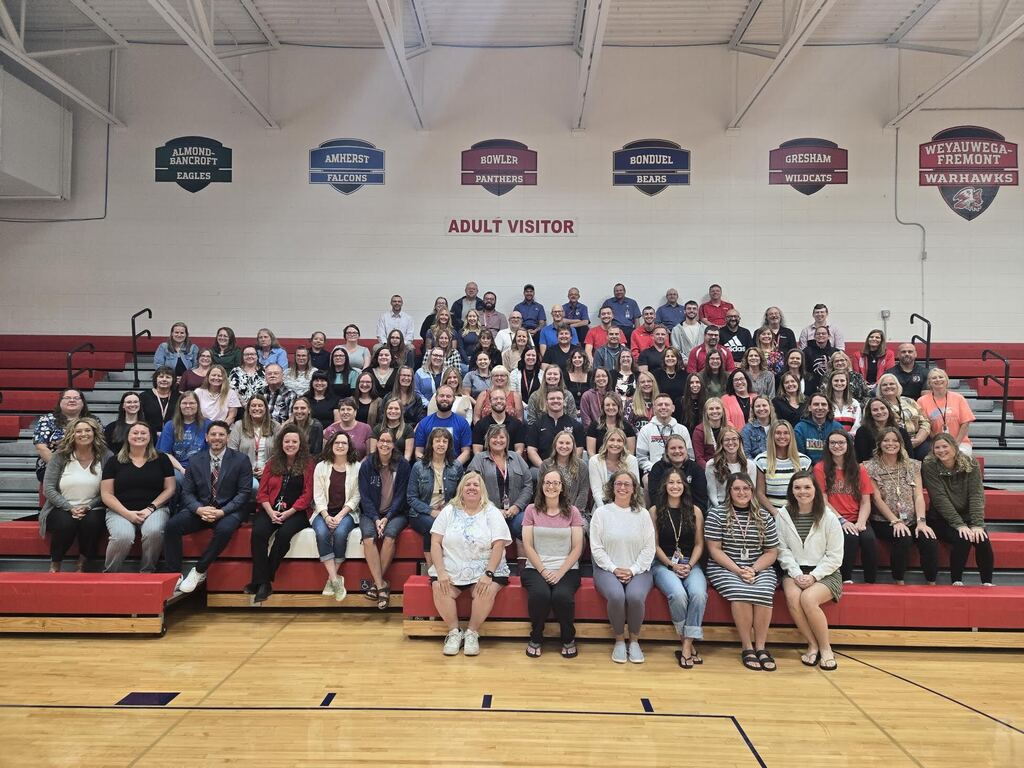 Group photo of the WFSD staff sitting in the gym bleachers smiling and ready for the new school year.
