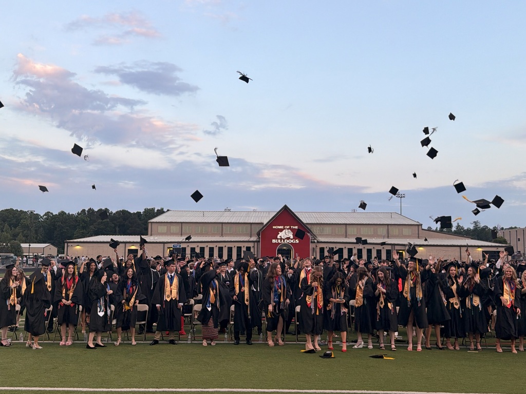 Graduates throwing caps in the air at. Bulldog Stadium