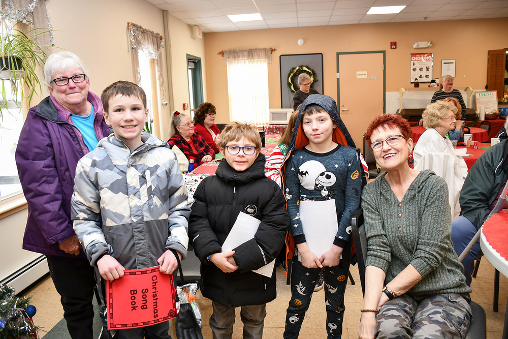 Two fourth graders from the Tioughnioga Riverside Academy pose for a photo with patrons of the Northern Broome Senior Center, where they just finished singing Christmas carols.