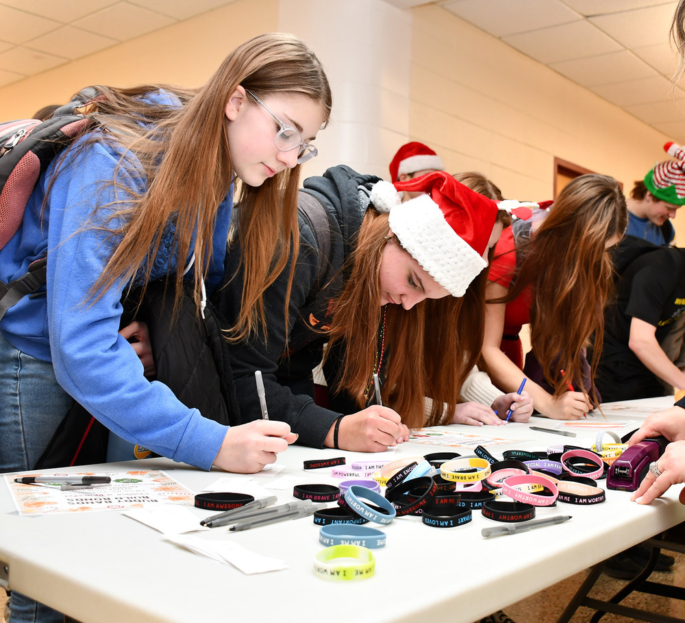 Students filling out a message to go with a rubber Buddy Band bracelet they are sending to someone to uplift them.