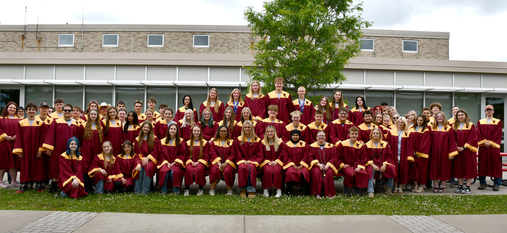 The Class of 2026 Whitney Point High School seniors in their maroon and gold gowns in front of the high school.