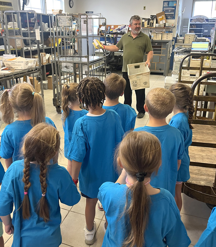 C E A  Kindergarten students listen to a postal worker talk about how mail is sorted at the post office.