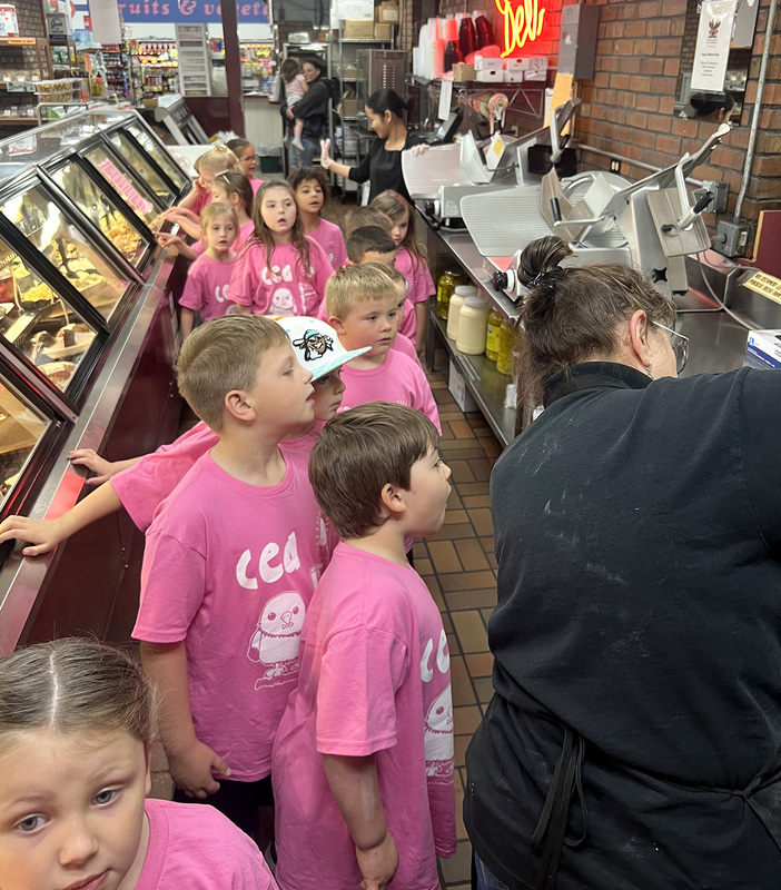 C E A  Kindergarten students watch meat being sliced in the deli at Greggs market.