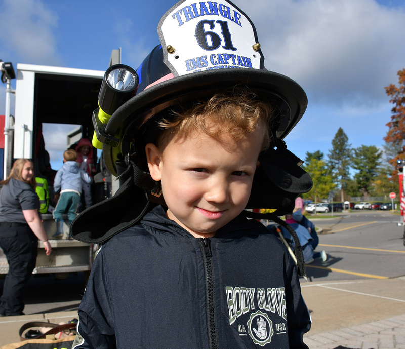A young student wearing a firefighters helmet.