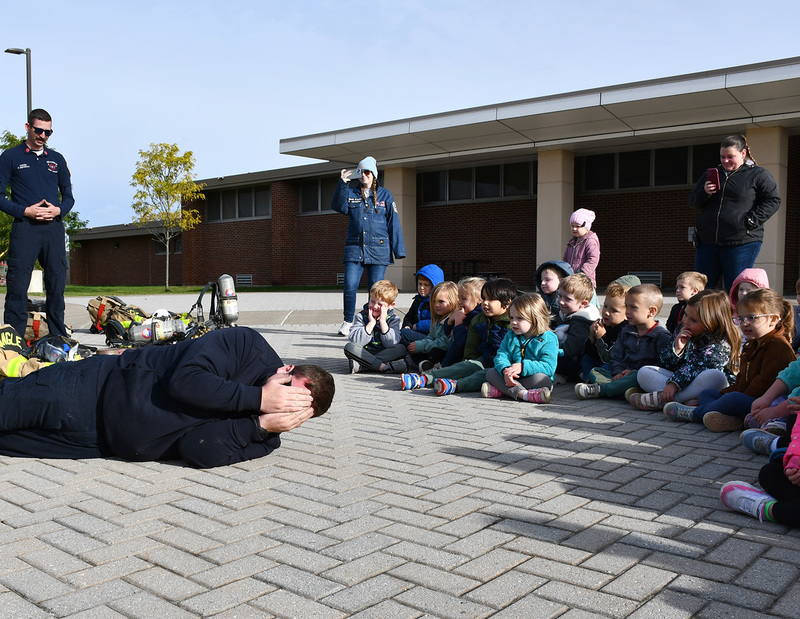 Triangle Assistant Fire Chief Chris Ryan demonstrates how to stop, drop, cover your face and roll for pre-kindergarten students at Whitney Point's Caryl E Adams Primary School.