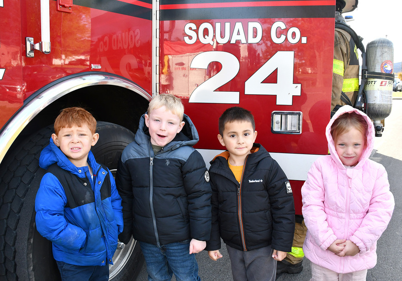 Four Pre Kindergarten students by the open door of Whitney Point Fire Departments Squad Company four fire truck.