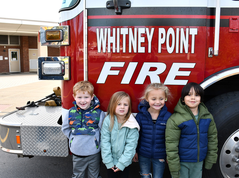 Four Pre Kindergarten students stand next to a Whitney Point Fire Truck that came to Caryl E Adams Primary School on October 24, 2025.