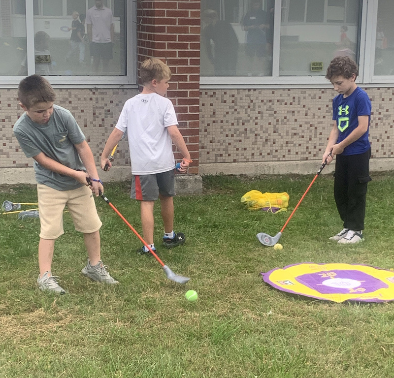 Caryl Adams students practicing golf outside with plastic clubs and balls.