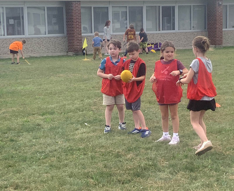 Four Caryl Adams students wearing red sports jerseys and one is holding a football.