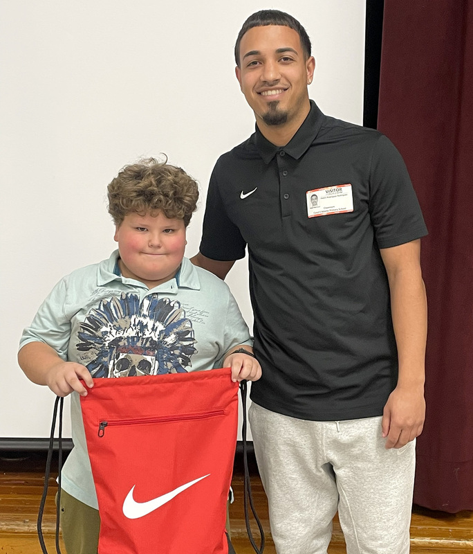 A Caryl Adams student holding a red cinch backpack with white Nike swoosh next to a SUNY Cortland student majoring in Physical Education.