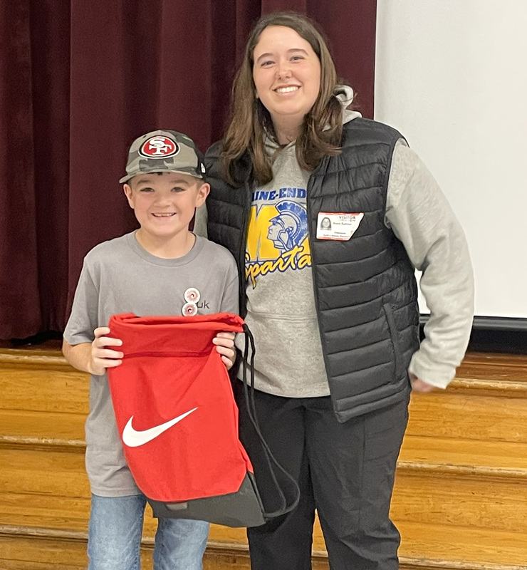 A Caryl Adams student holding a red cinch backpack with white Nike swoosh next to a SUNY Cortland student majoring in Physical Education.