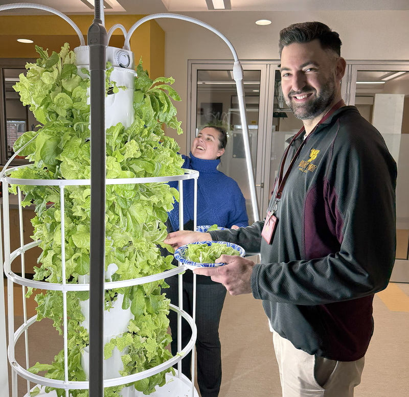 Principal Szweliga by the grow tower full of lettuce.