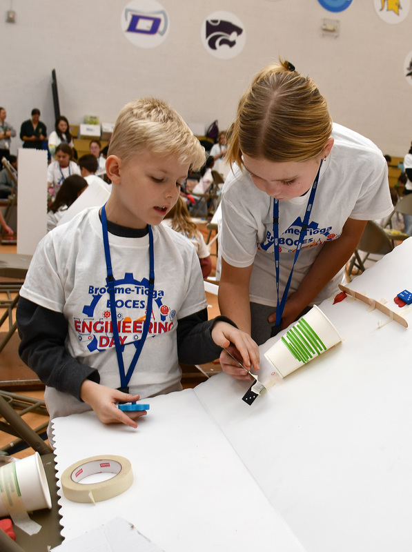 Two T R A students competing in the Elementary Engineering Day competition at Broome-Tioga BOCES discuss the placement of a paper cup on their design.