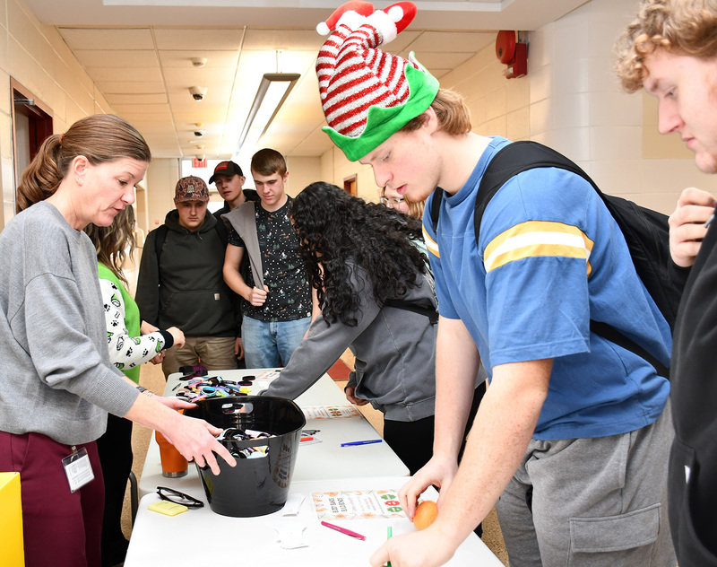 Principal Hawley helps students fill out positive messages of support to go with candy canes or buddy bands.
