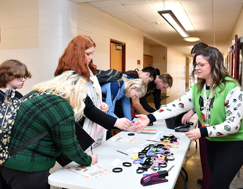 A Whitney Point High School student hands her the buddy band she has selected to a teacher to go with the message she wrote for a fellow student.