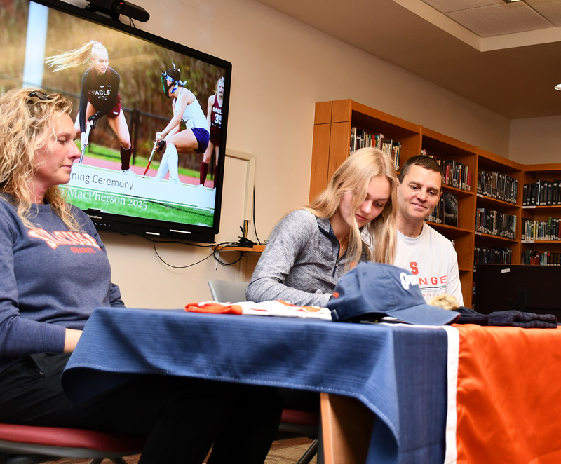 As her parents watch, Genevieve Huston signs her national letter of intent to play field hockey at Syracuse University.