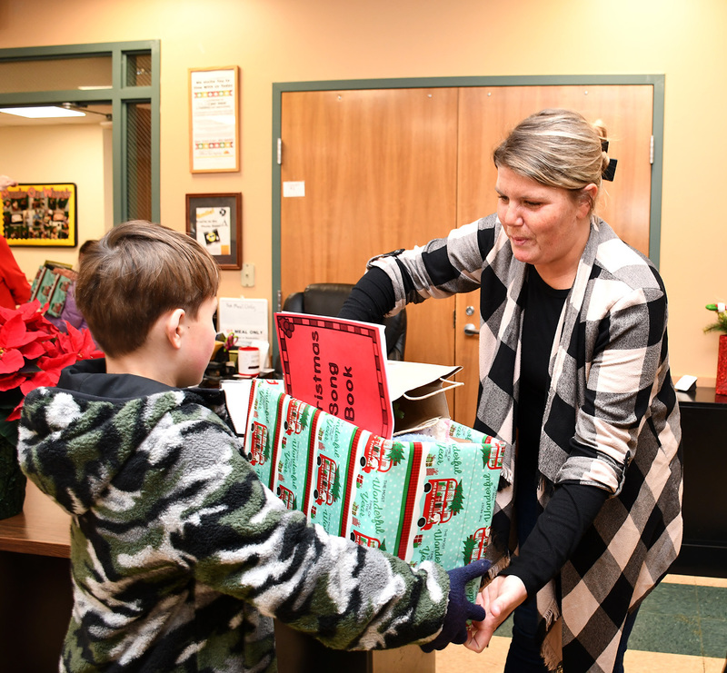 A fourth grader gives a staff member at the Northern Broome Senior Center a box of gifts he and the other fourth grade classes collected to gift to the senior citizens who visit the center.