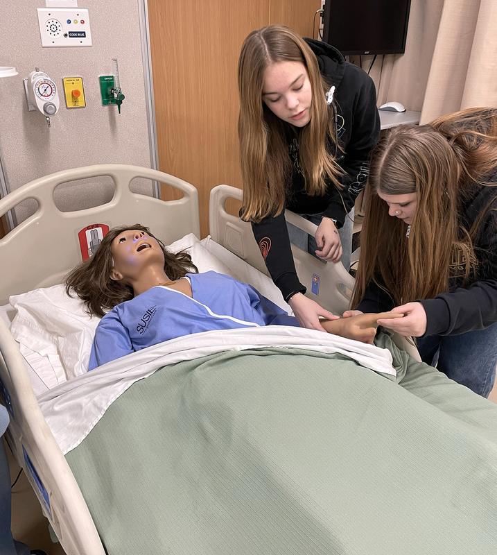 Two eighth graders work on a practice dummy in the nursing unit at the Decker Health and Science Center at SUNY Broome.