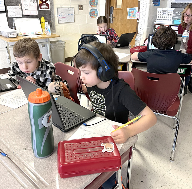 Two Caryl Adams Primary School students work on laptops at their desks.