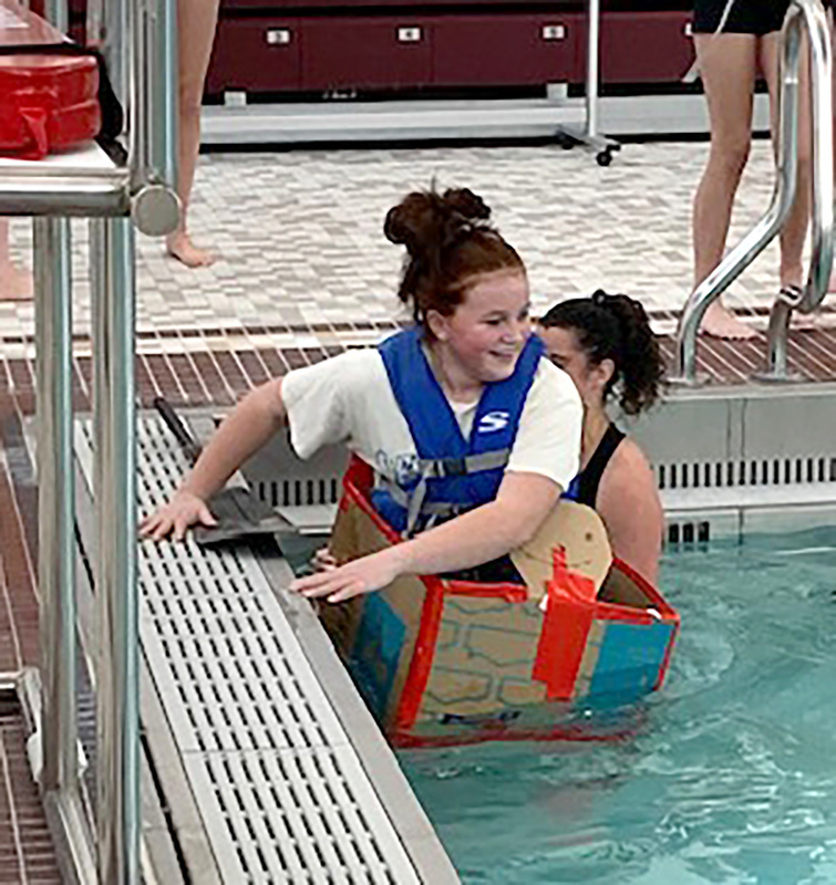 A student prepares to launch herself in her cardboard vessel in the Whitney Point swimming pool.