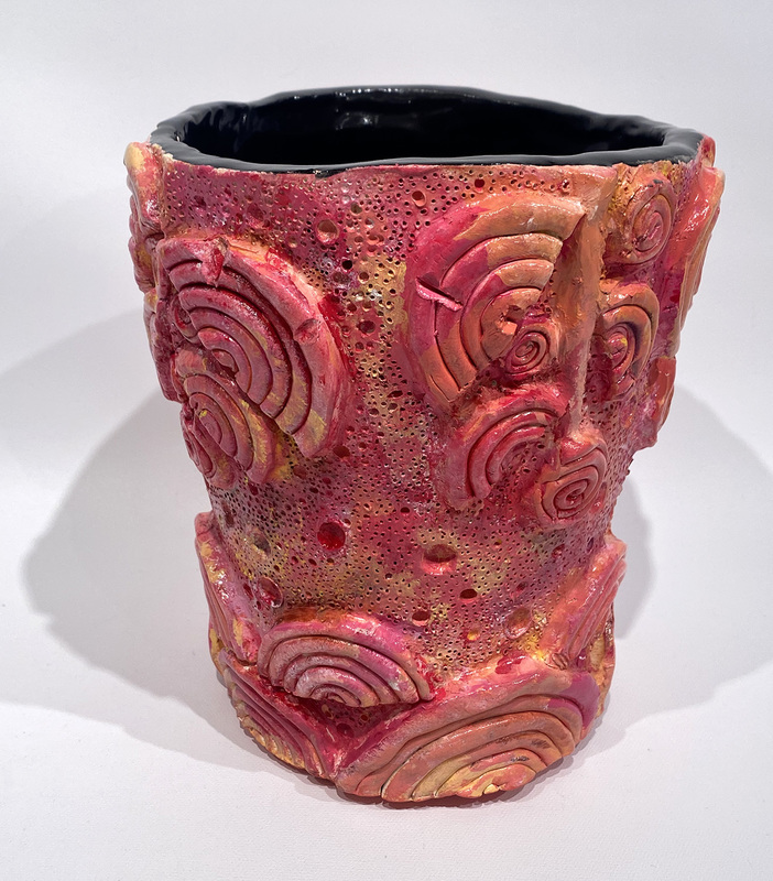 Three-dimensional elements that look like shells embellish this ceramic post glazed in reds, pinks, oranges, and yellows.