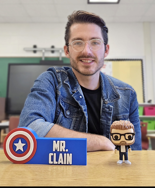 Mr Clain at his desk in a second grade classroom at Caryl E. Adams Primary School.